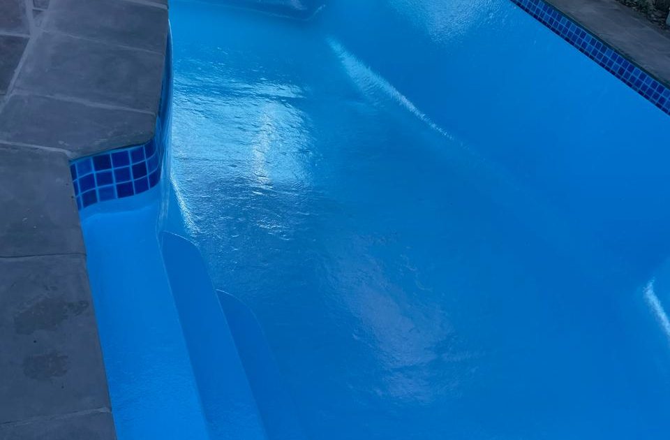 A modern, newly remodelled swimming pool in a Cape Town backyard featuring clean lines, fresh fibreglass surfacing, updated paving, and a serene entertainment area.