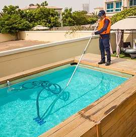 Professional pool technician vacuuming a residential swimming pool for routine maintenance in Cape Town.