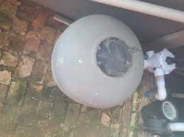 Sand filter, multiport valve and pump squeezed into a brick corner, where unions and valves can drip