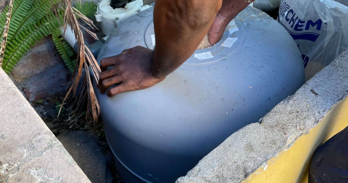 Technician cleaning a sand pool filter with old sand removal in Kenwyn, Cape Town – professional pool maintenance and filter servicing.