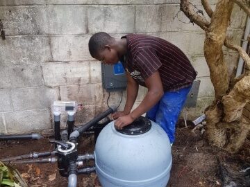 Pool technician maintaining pool filter and chlorinator in Paarl