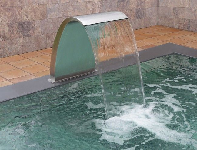 Unique custom design of a concrete gunite pool with water features.