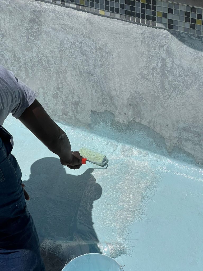 Technician sealing a repaired section of pool shell after a crack repair
