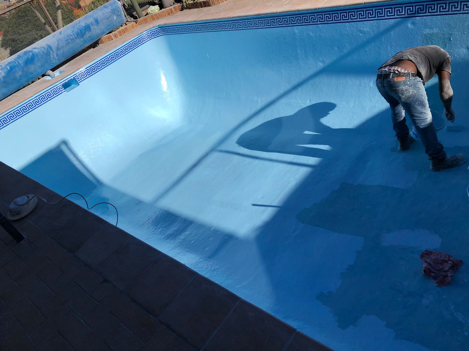 Pool technician painting the interior of a residential swimming pool in Cape Town