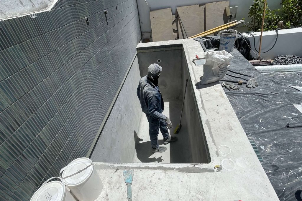 Splash pool shell being built in a tight space between a boundary wall and the house