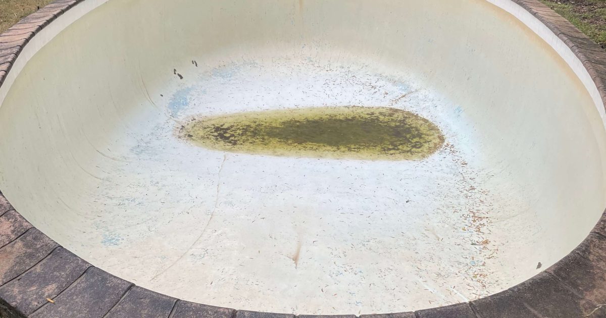 Empty inground swimming pool with visible surface cracks under Cape Town sun, highlighting risks of draining without professional guidance.