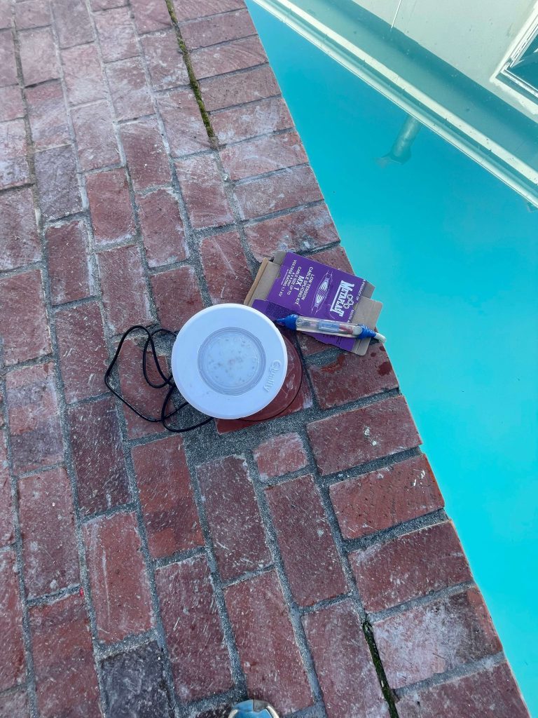 New LED pool light ready to replace an old halogen lamp at the edge of a pool