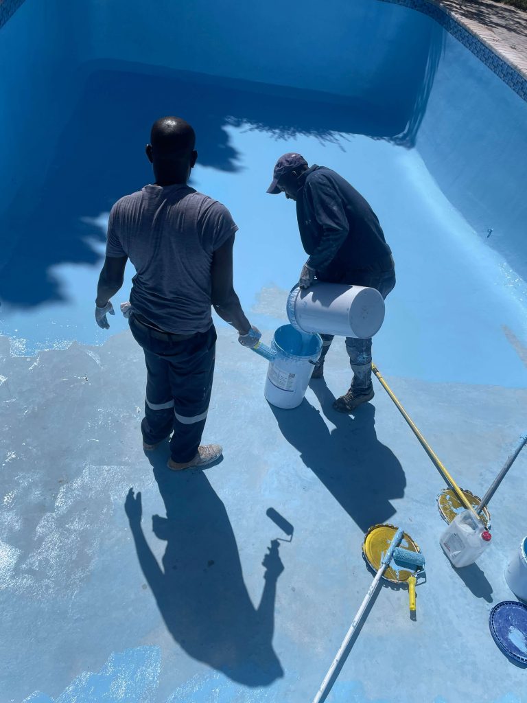 Pools Reno technician painting a freshly fibreglass lined swimming pool in Cape Town, applying durable, UV-resistant pool coating for a smooth, vibrant finish.