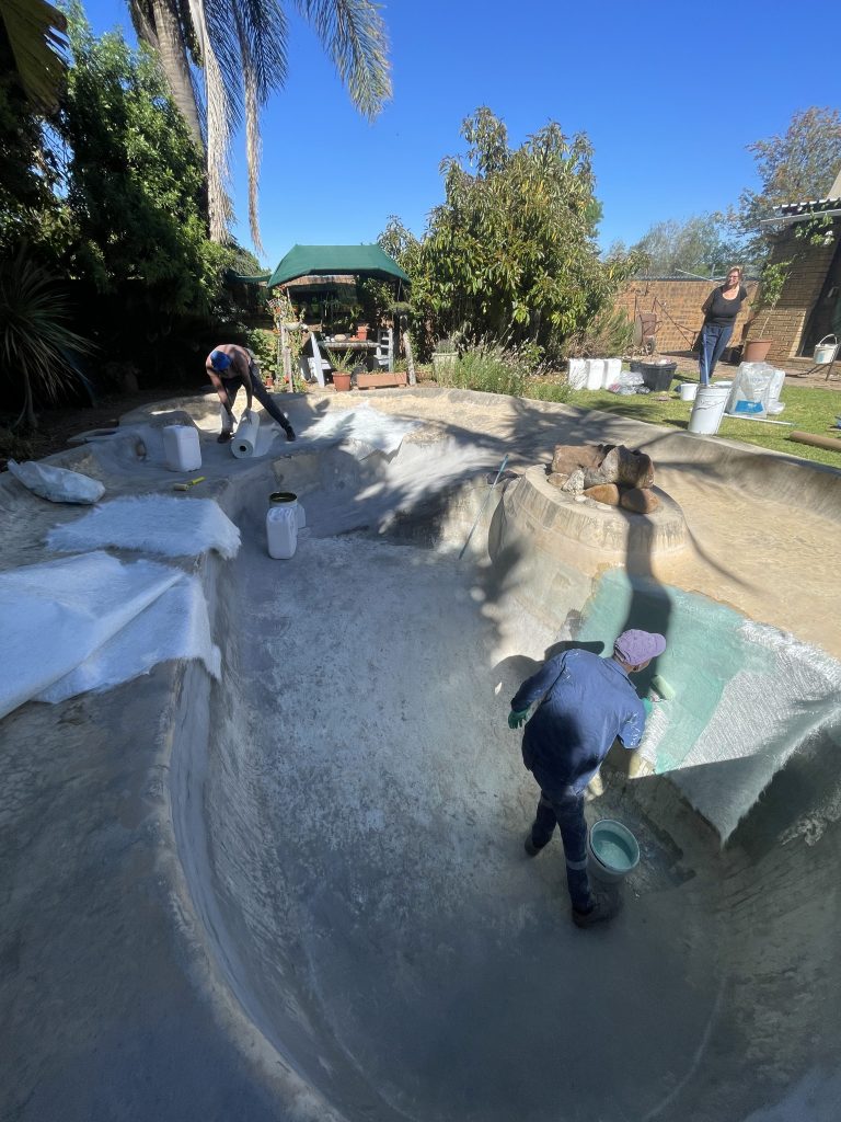 Pools Reno team applying a new fibreglass lining to a beach entry swimming pool in Cape Town, creating a smooth, durable, and watertight surface ready for painting.