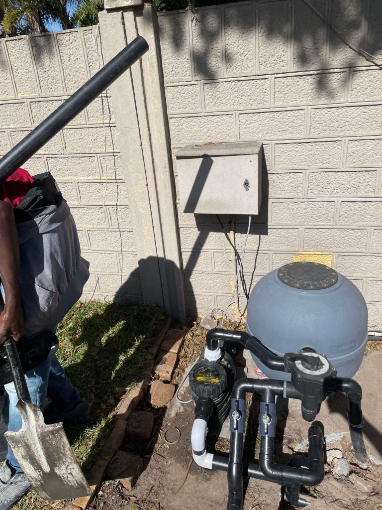 Pool equipment area with pump, sand filter and a wall-mounted electrical box