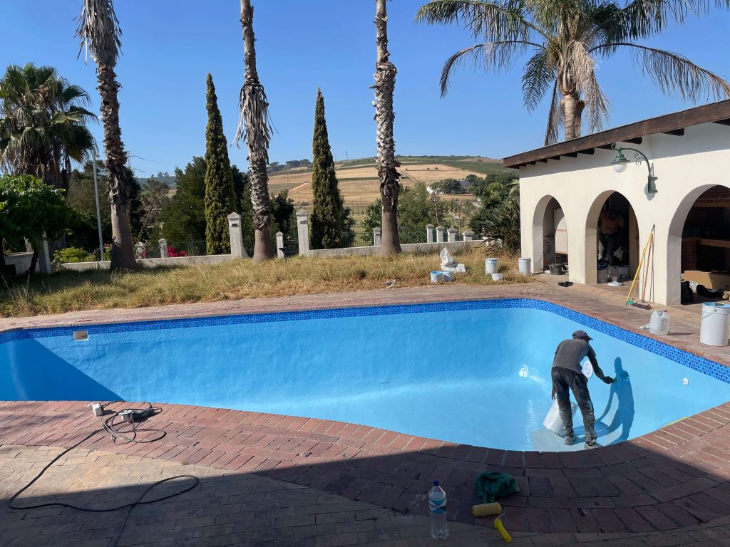 Final painting and finishing of a fibreglass-resurfaced marbelite pool in Cape Town, giving the pool a fresh, modern look