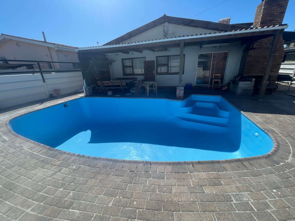 Newly fibreglass lined and painted swimming pool after full renovation, including surface repairs and paving, completed in Cape Town