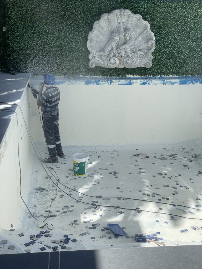 Removal of old ceramic mosaic tiles from a fibreglass lined concrete swimming pool during renovation in Cape Town