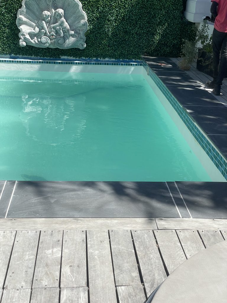 Finished fibreglass lined concrete swimming pool with new ceramic mosaics refilled with clear water in Cape Town