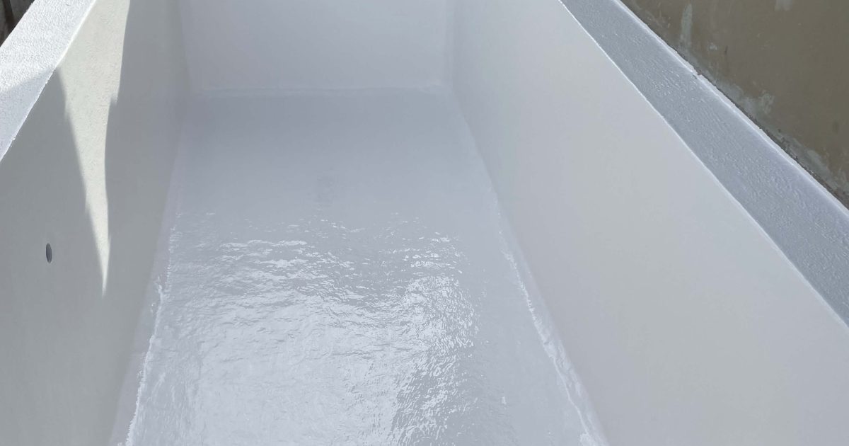 Professional pool technician painting a newly fibreglass-lined swimming pool in Mitchells Plain, Cape Town for a smooth and durable finish