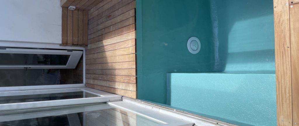 Underwater pool light fitting set into the wall of a relined splash pool beside timber decking