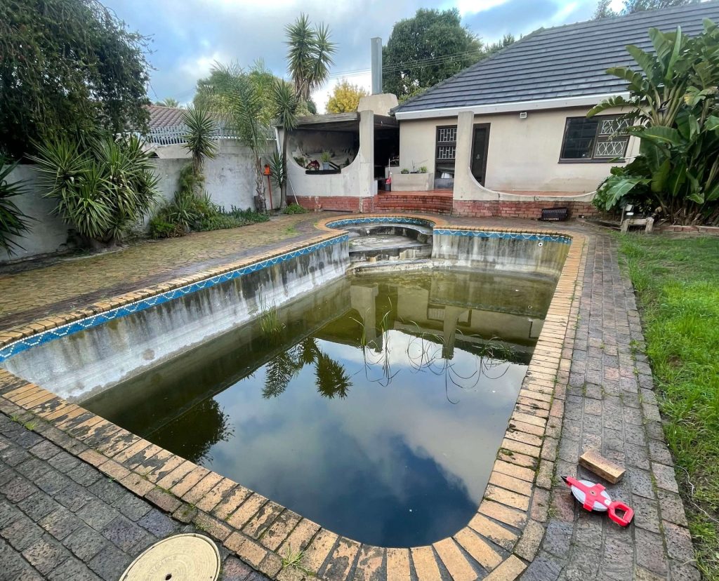 Ageing concrete pool in Bellville before resurfacing, with a worn and stained surface