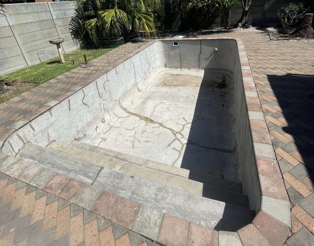 Cracked and stained marbelite swimming pool surface before renovation in Cape Town