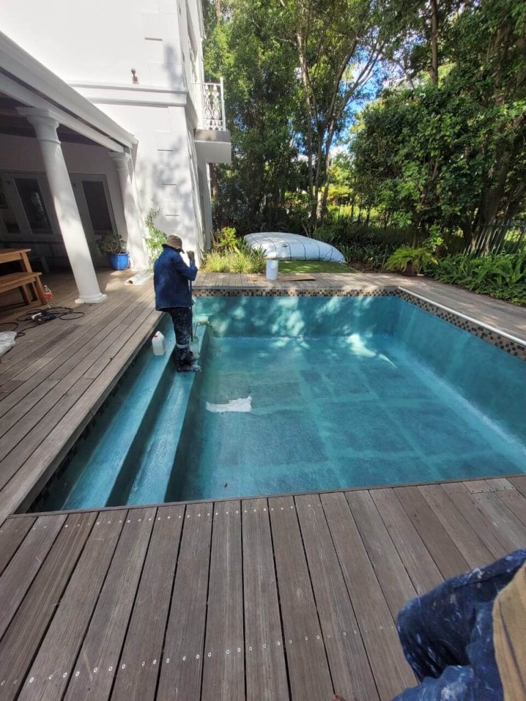 Technicians applying fibreglass matting and resin inside a swimming pool in Tableview Cape Town during pool relining process