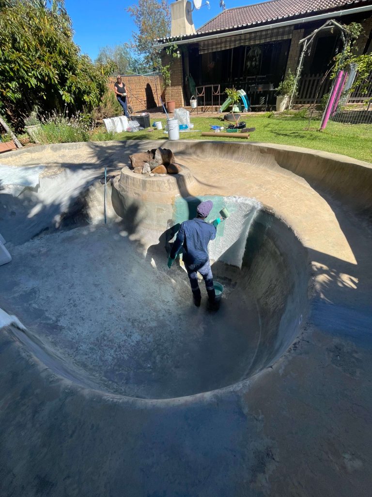 Technicians applying fibreglass layers inside a swimming pool in Stellenbosch during pool relining and resurfacing process