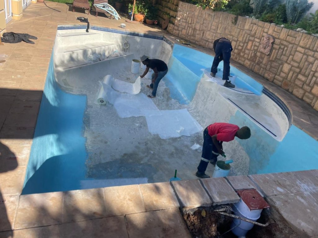 Fibreglass lining process of a swimming pool in Strand Cape Town showing pool resurfacing installation in a coastal environment