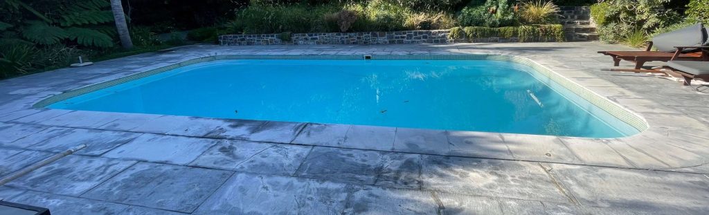 Marbelite pool with bright blue water beside a timber deck after resurfacing