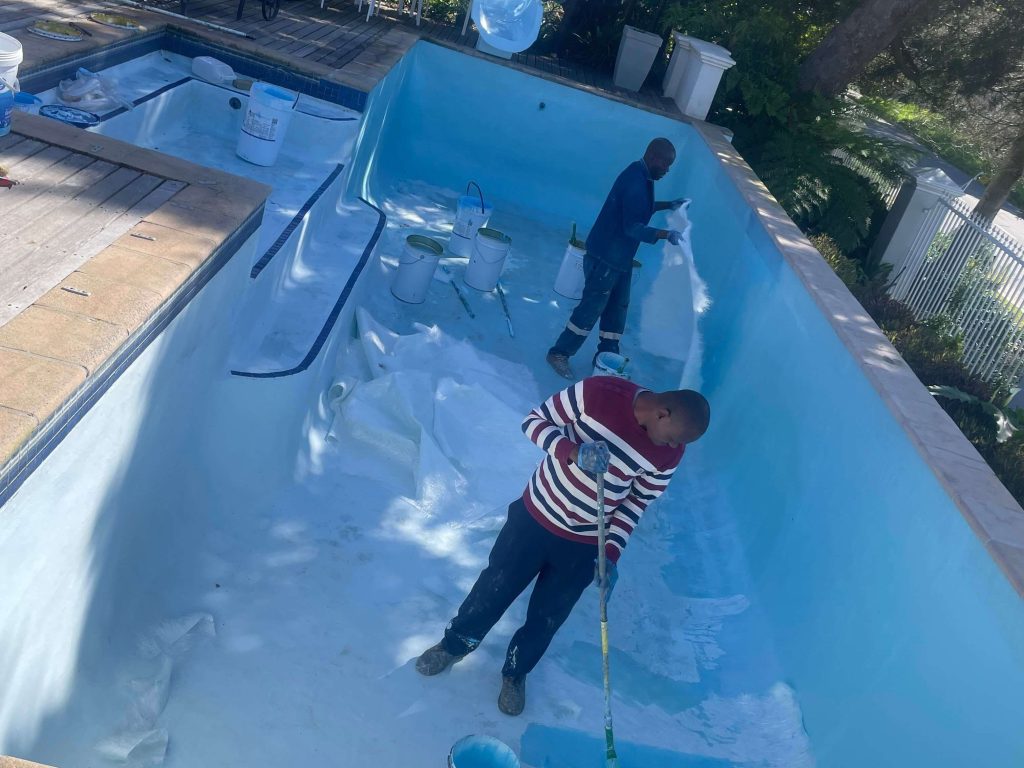 Technicians laying new fibreglass matting and resin while relining a swimming pool