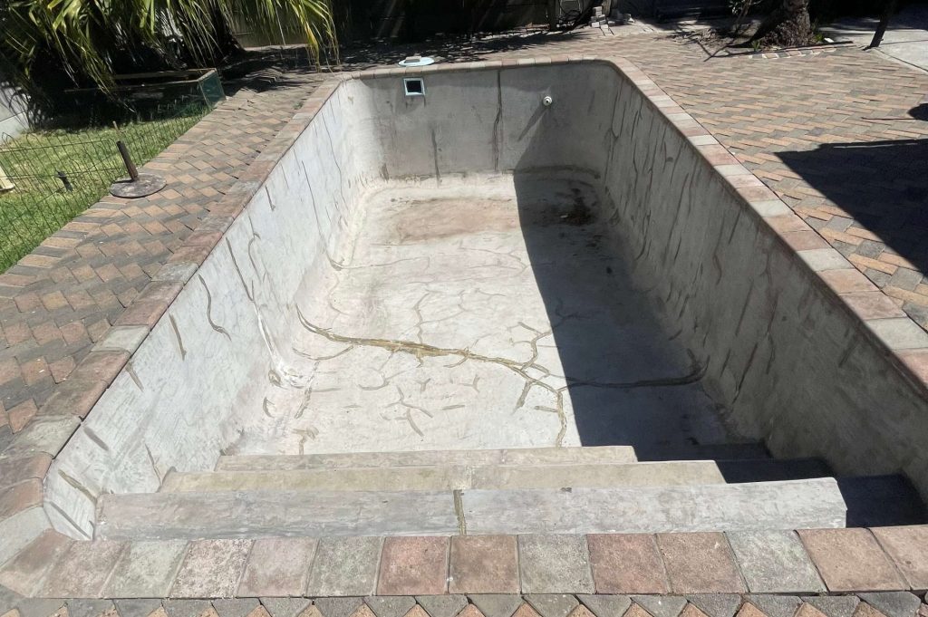 Cracked and stained marbelite swimming pool in Kleinmond before fibreglass relining and renovation