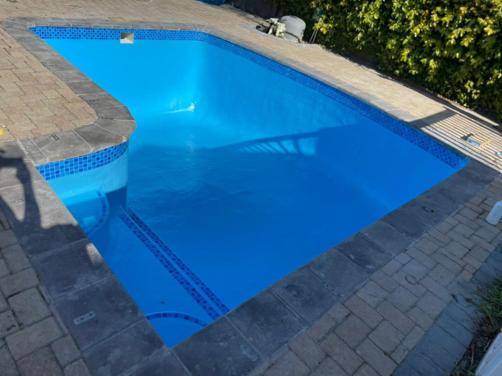 Clean marbelite swimming pool after rust stain removal and resurfacing showing smooth blue finish in Cape Town