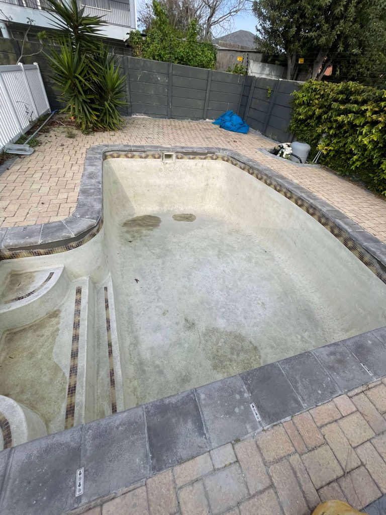 Severe rust and iron stains on a marbelite pool surface before professional pool stain removal in Cape Town