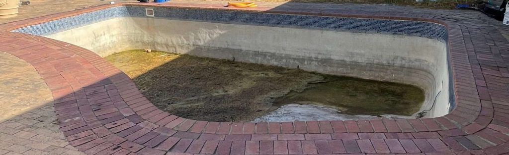 “Old cracked marbelite swimming pool in Piketberg showing algae staining, surface erosion and structural wear before renovation”
