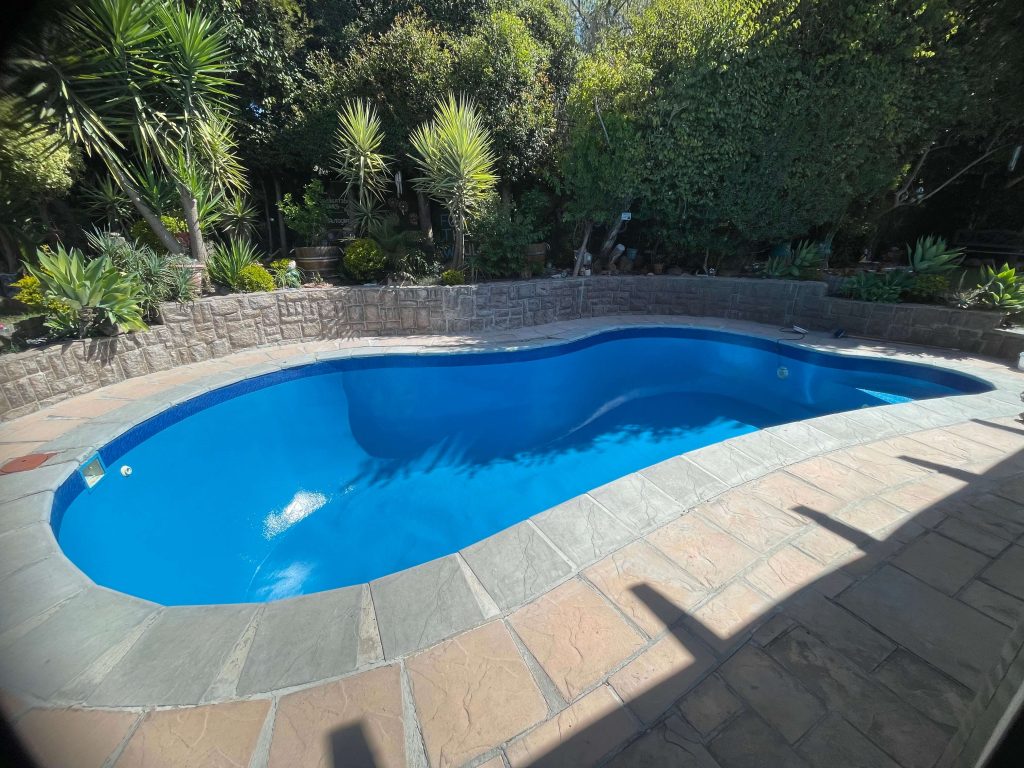 Swimming pool renovation in Melkbosstrand showing before and after fibreglass lining and painting with modern smooth blue pool finish