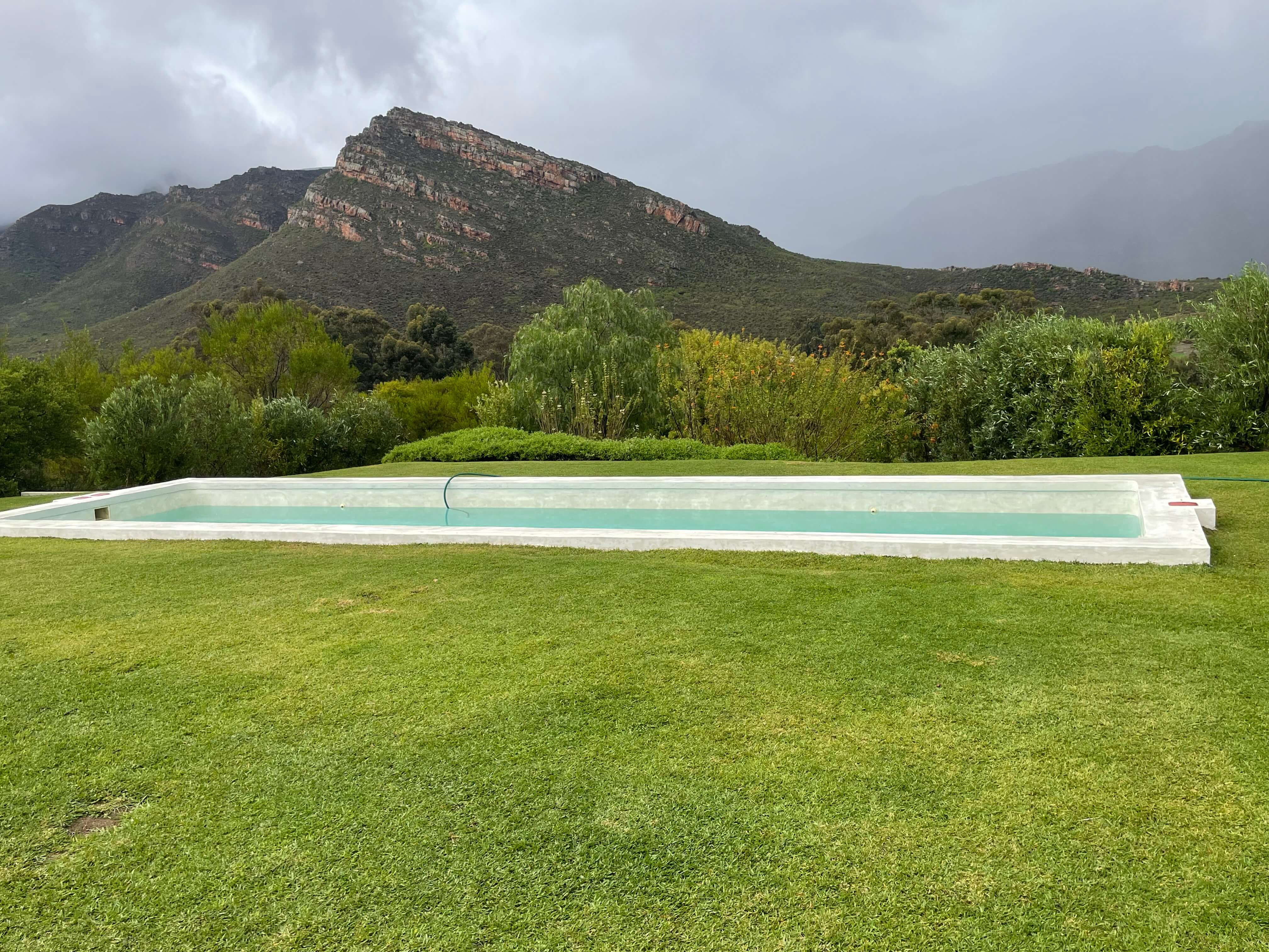 “Renovated fibreglass swimming pool in Piketberg Western Cape on farm property with mountain and agricultural landscape background”