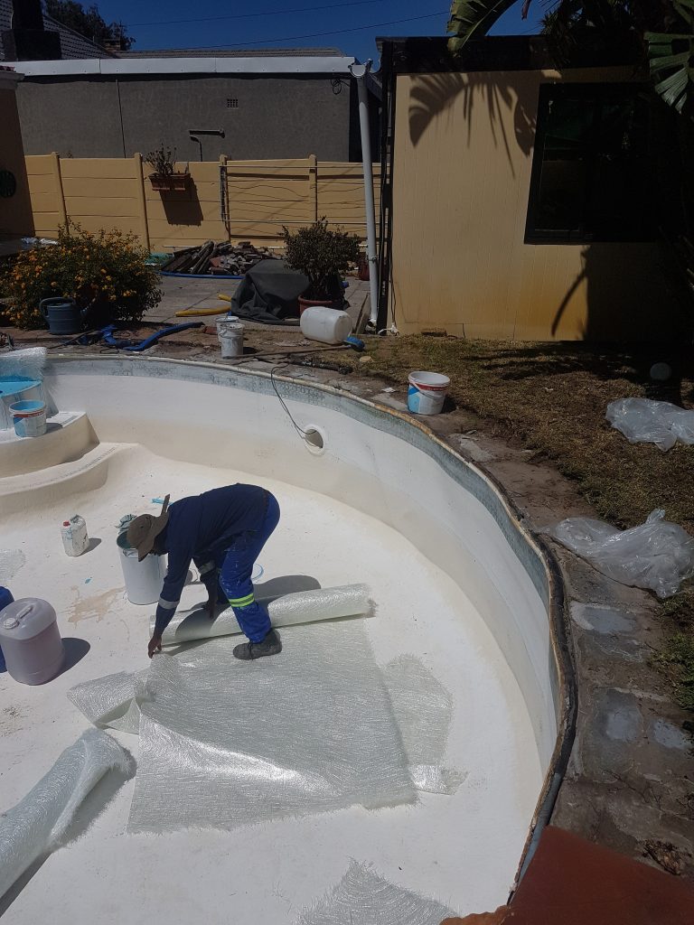 “Pool technician applying fibreglass lining system during swimming pool renovation in Riebeek-Kasteel Western Cape”