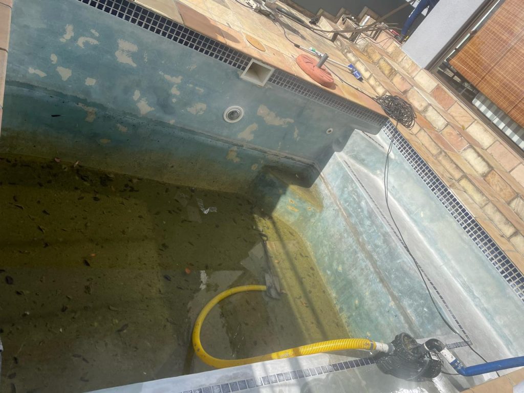 "Damaged marbelite swimming pool in Darling Western Cape before renovation showing cracks and surface erosion"