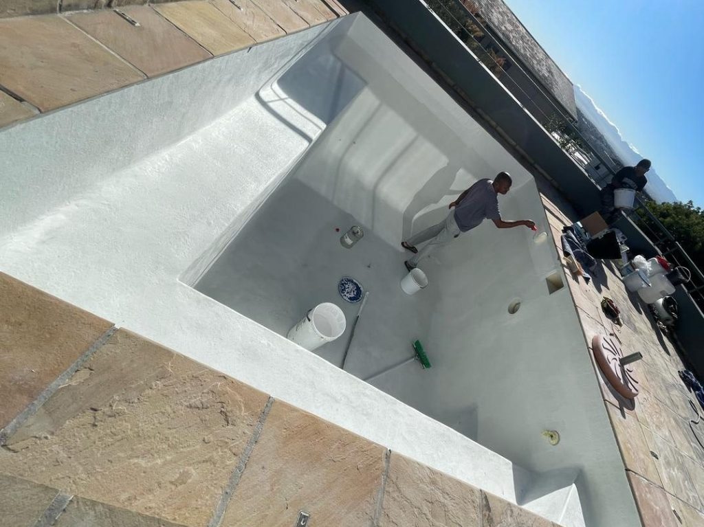 “Pool renovation technician applying fibreglass lining system to swimming pool in Philadelphia Western Cape”