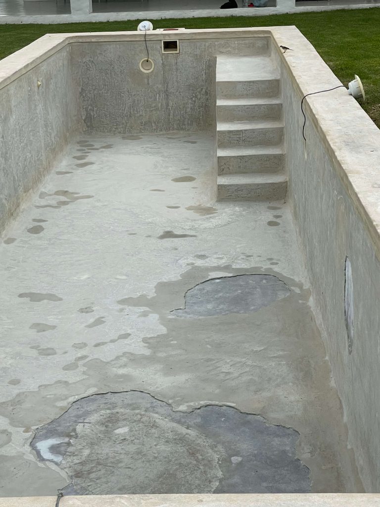 Old cracked marbelite swimming pool in Tulbagh showing surface erosion, discoloration and structural wear before renovation