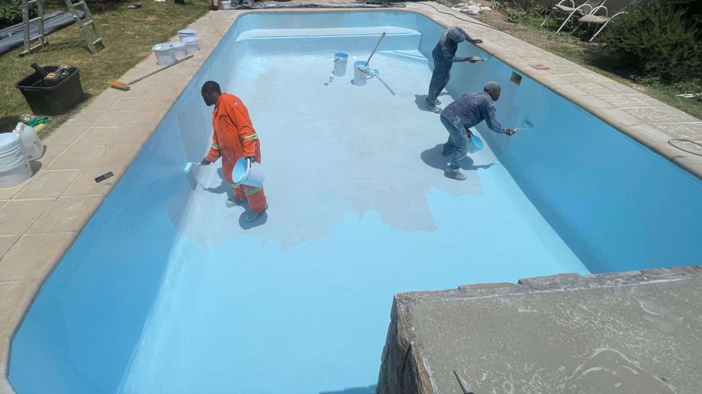 Blue fibreglass flow coat finish being applied to renovated swimming pool in Yzerfontein