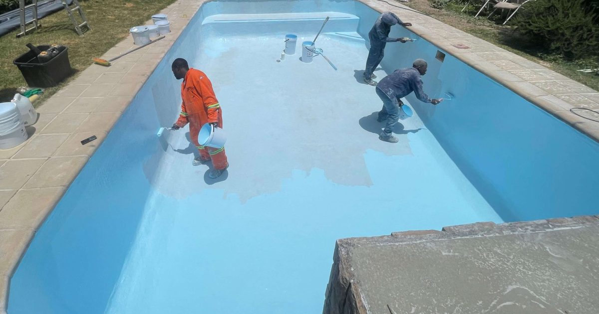 Blue fibreglass flow coat finish being applied to renovated swimming pool in Yzerfontein