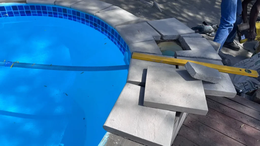 Coping slabs being set at the pool edge with a spirit level