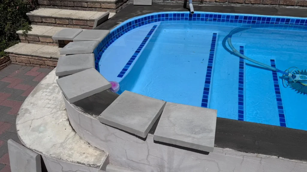New bullnose copings being laid around the curved end of the pool