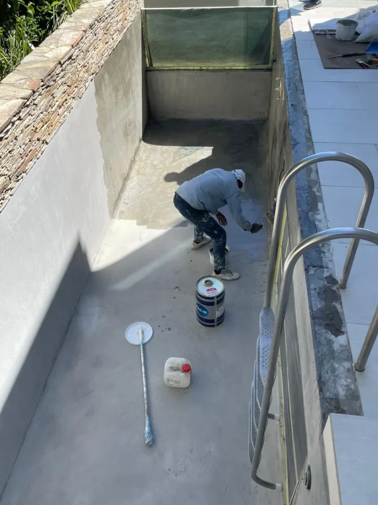 Team member priming the plastered floor of the lap pool before the fibreglass goes on