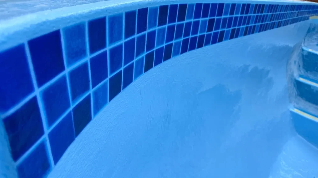 Close-up of new blue tissue mosaic tiles at the waterline above the smooth fibreglass