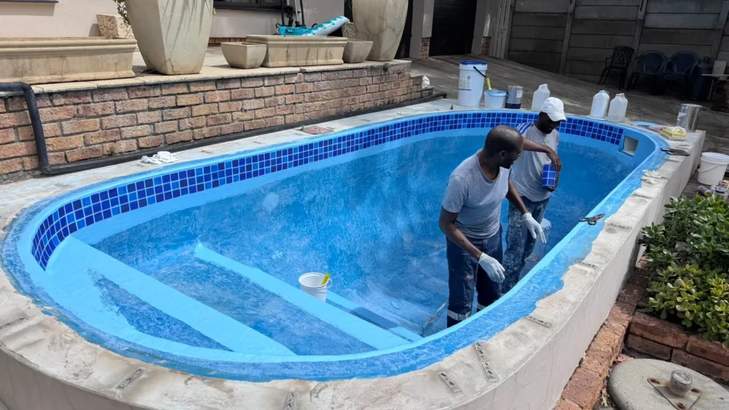 Team members working on the steps of the pool after the mosaic waterline band was fitted