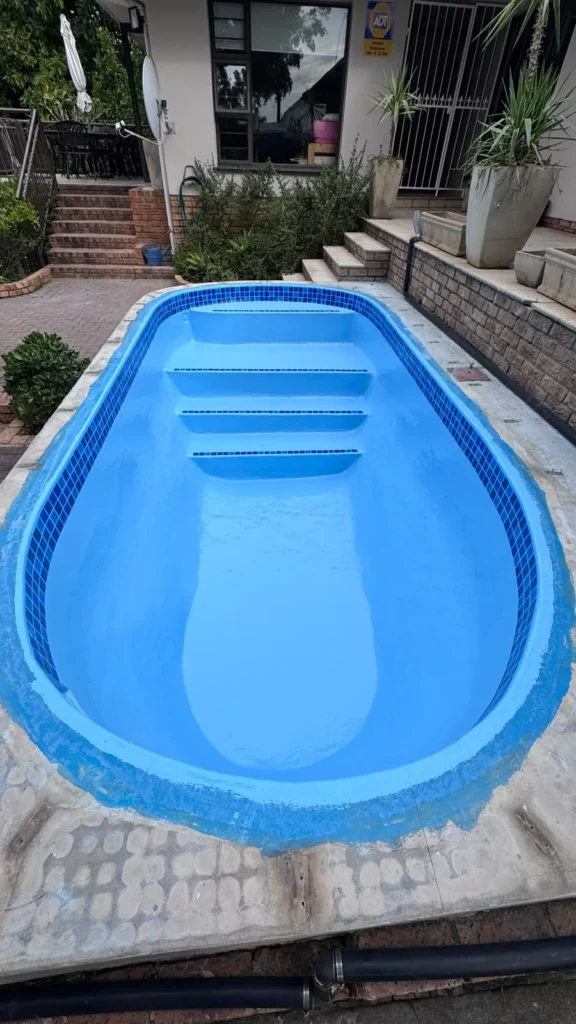 Finished fibreglass relined pool with mosaic waterline and tiled step edges, still empty