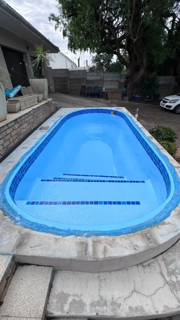 Finished relined pool seen from the deep end, with tiled step edges at the far end
