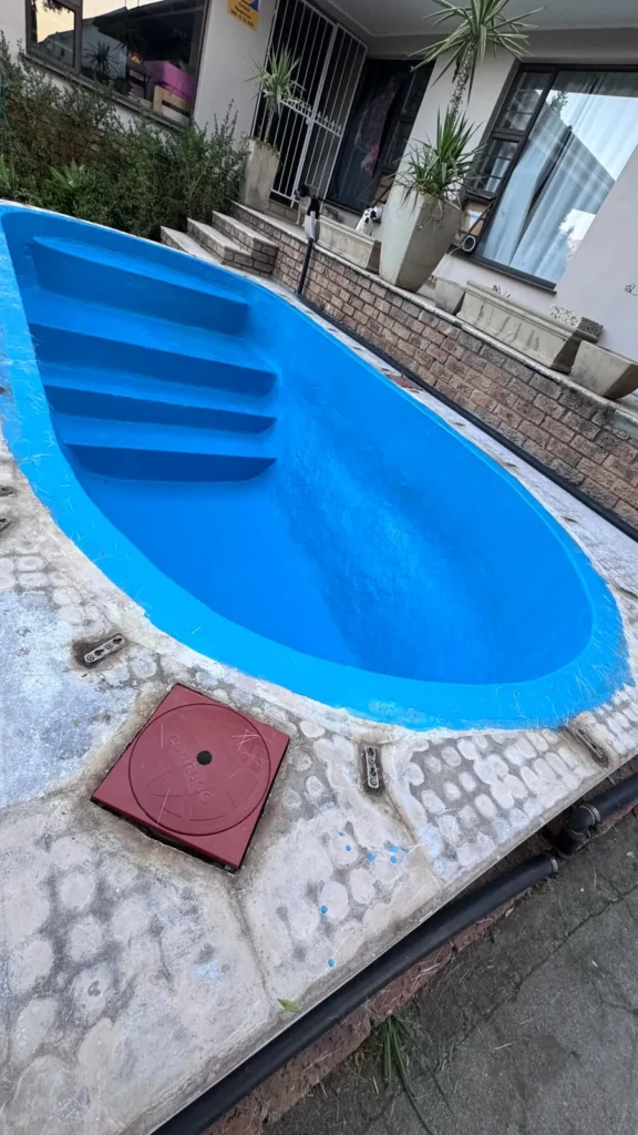 Shallow end steps of the finished fibreglass pool next to a pump room access lid