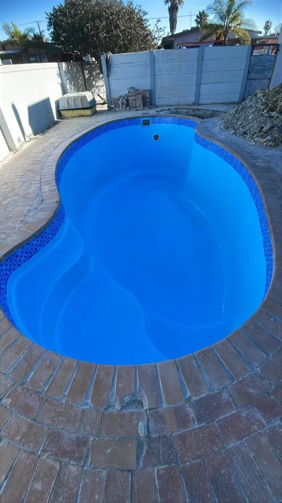 Finished freeform pool full of water with a blue tissue mosaic waterline