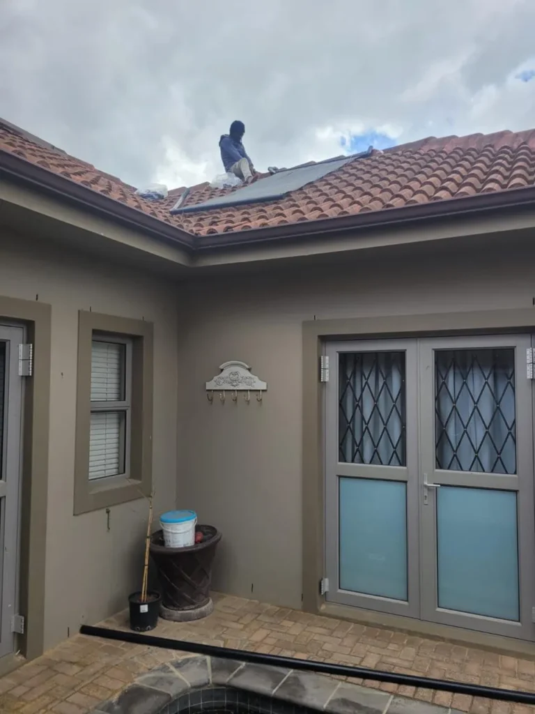 Team member on a tiled roof fitting solar pool heating panels