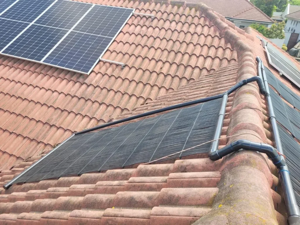Solar pool heating panels on a tiled roof with the pipework running over the ridge